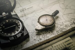 shallow focus photography of black and silver compasses on top of map